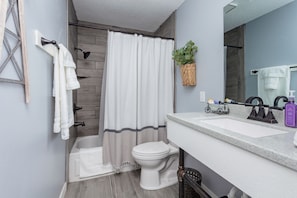 Stocked bathroom upstairs with toilet paper, toiletries, towels, a hair dryer.