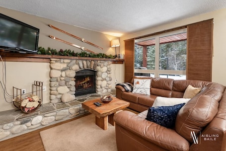 Living room with a smart TV, a cozy sectional and decorative fireplace (glow logs only due to strata regulations.)