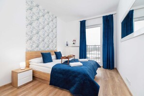 A bedroom with a wooden bedframe, blue bedding, and a patterned wallpaper as a decorative backdrop.