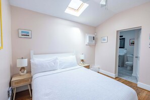 Queen bed includes bedside lighting and skylight, allowing for ample light
