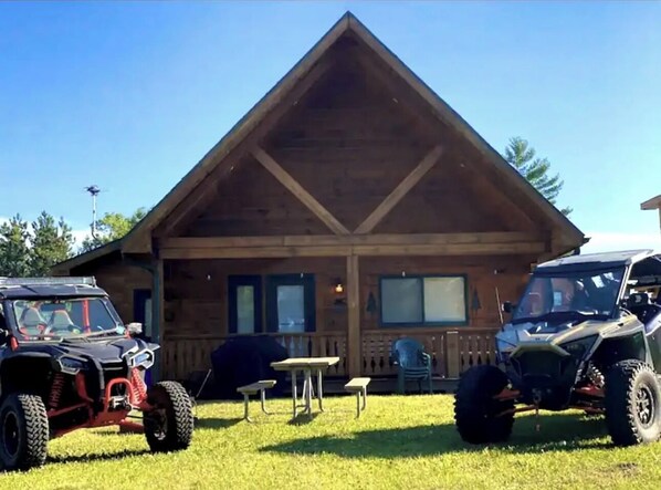 Front of the cabin facing backyard with UTV's parked