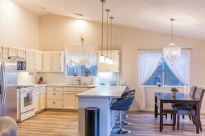 Fully Stocked Kitchen and Dining Area: Cook and dine with ease in this bright kitchen featuring ample counter space, and a stylish dining table for four.