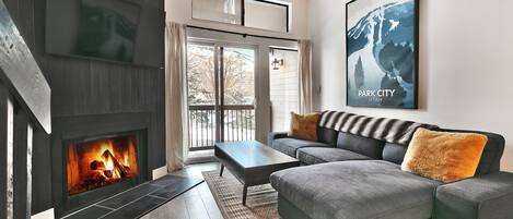 Modern living room with wood burning fireplace, gray sectional couch and sliding glass doors to private patio