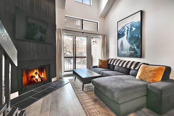 Modern living room with wood burning fireplace, gray sectional couch and sliding glass doors to private patio