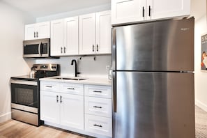 Fully equipped kitchen, stainless steel appliances and white wood cabinets