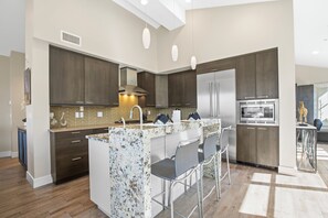 Open concept kitchen with waterfall island and stainless steel appliances.
