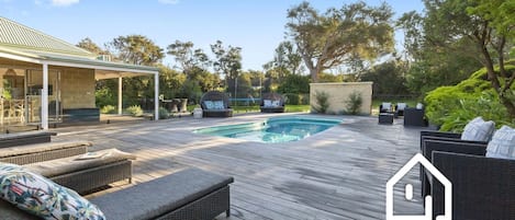 Solar heated pool surrounded by a huge fenced deck, trampoline & outdoor seating