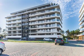 The front of a modern apartment complex with paved walkways and neatly arranged parking spaces.
