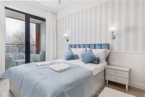 A cozy bedroom with a large bed adorned with blue pillows and bedding, complemented by matching curtains.