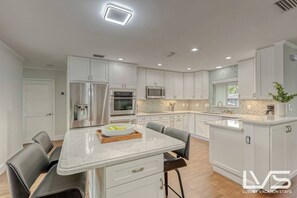 Open layout fully appointed eat in kitchen with island for 4, stainless steel refrigerator with filtered water/ice maker, Keurig machine for pod or regular drip coffee, toaster, microwave, filtered water etc.  Look on listing for a detailed list of everything located  inside kitchen. 