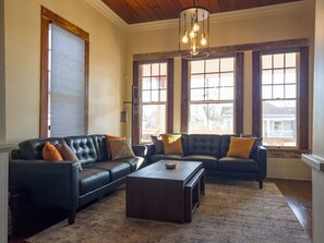Living room with TV, 2 comfortable sofas, lots of natural light & blinds.