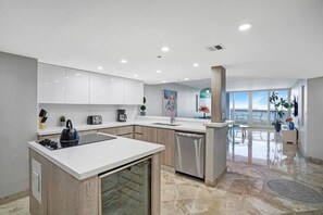 Fully equipped kitchen with washer/dryer, view into dining/living room