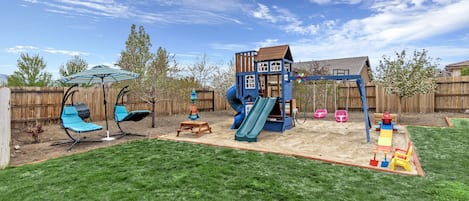 Sandbox, play structure, 4 blue swinging lounge chairs, and seasonal pool