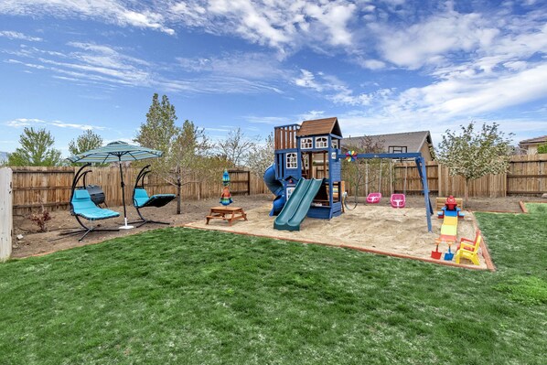 Sandbox, play structure, 4 blue swinging lounge chairs, and seasonal pool