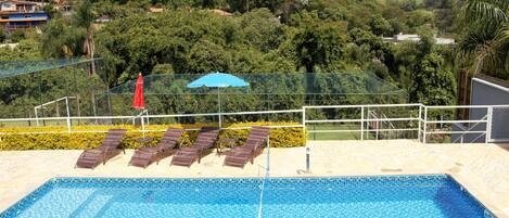 Piscina com vista para a natureza e campinho de futebol.