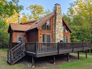 Log cabin, with large deck including grill, and patio set.