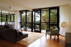 Lounge room onto balcony overlooking  palm trees and bushland