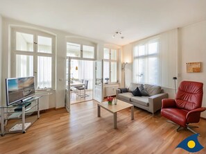 Wohnzimmer mit offener Küche und Zugang zum Balkon