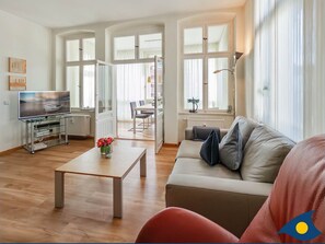 Wohnzimmer mit offener Küche und Zugang zum Balkon