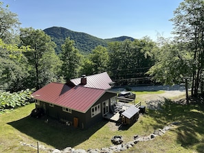 Summer view of house with deck, BBQ, fire pit and outdoor space.