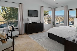 Luxe Master Suite: Panoramic Desert Views & Modern Comfort...Enjoy the spacious master bedroom, vaulted ceiling and modern ceiling fan, Comfortable king-size bed, Seating area with TV, Elegant tile flooring, and Contemporary furnishings and decor.