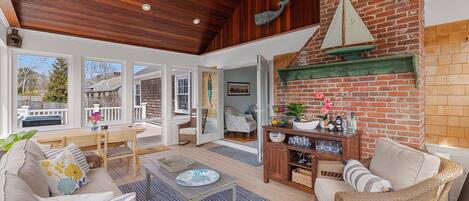 Spacious sunroom with vaulted mahogany ceilings and dining table.