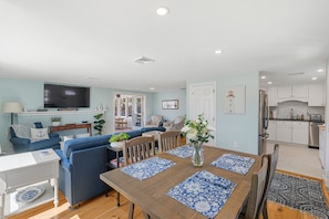 Dining area and living room with large flat screen TV and view of kitchen.