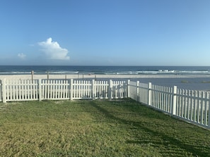 View of the beach and fenced yard from the ground level patio.