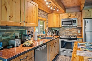 Cook up cabin comfort with a full-size gas range, set against a natural stacked stone backsplash for rustic elegance.