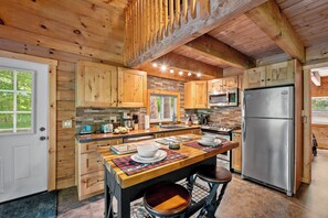 Cook in comfort with a fully stocked kitchen featuring stainless steel appliances and rustic charm.