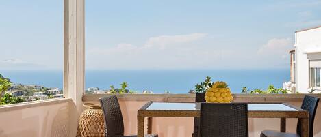 Sea view shared patio with tables, sofas with high pillows and hanging chairs