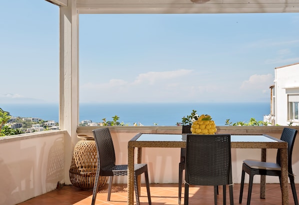 Sea view shared patio with tables, sofas with high pillows and hanging chairs