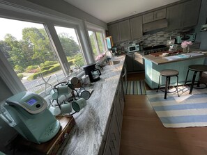 Kitchen overlooks picket fence lined front yard, English garden and Cove.