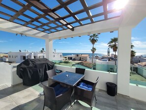 View from kitchen, pergola with propane grill and seating. 