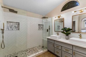 Spa like bathroom with double shower head, two personal showers, and bench.