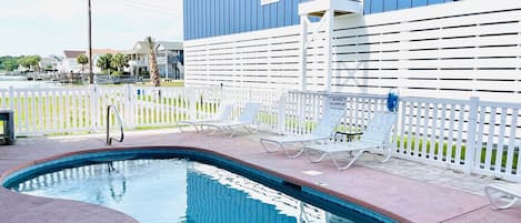 Large pool area with loungers and a table and chairs