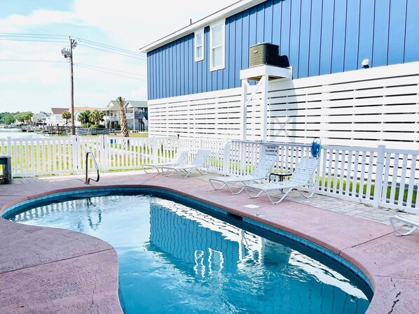 Large pool area with loungers and a table and chairs