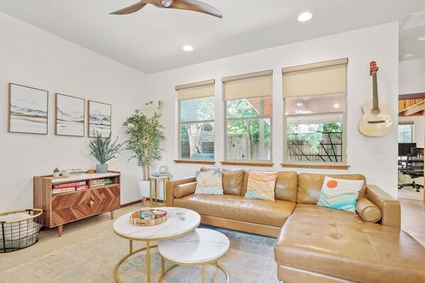 Livingroom with leather sectional, hutch of board games, smart TV and guitar