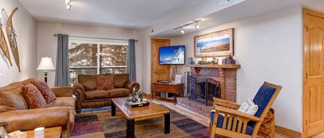 Living Room with gorgeous suede furnishings, sofa bed, wood-burning fireplace, Samsung smart TV, and private balcony access