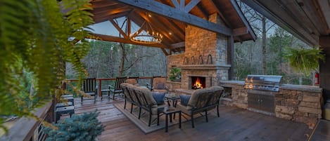 River Joy Lodge- Entry Level Deck Covered Fireplace Seating Area at Dusk