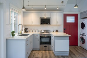Modern kitchen with electric stovetop and oven, Blomberg stackable washer and dryer.