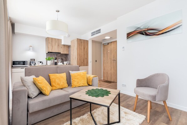 A bright, cosy living room space where the seating area is combined with the dining area. A decorative black carpet lies on the floor.
