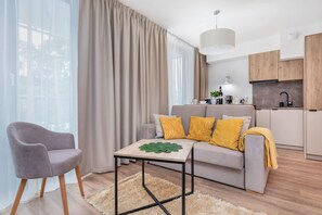 A wider perspective of a cosy and stylish space that combines a seating area with a dining area. In the background is the kitchenette.