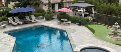 Backyard area with pool, spa, private deck area with pergola and 3 hole putting green. This shows the back of the guest house.