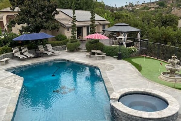 Backyard area with pool, spa, private deck area with pergola and 3 hole putting green. This shows the back of the guest house.