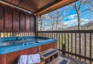 four-person hot tub with woods and seasonal mountain view on the back deck