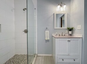 Shower Area with small vanity mirror and cabinet