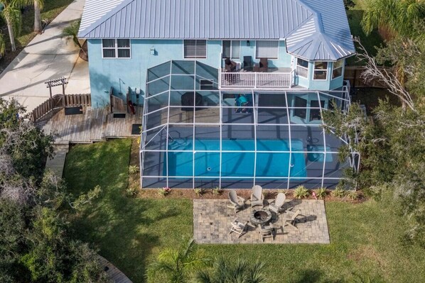 Experience ultimate outdoor relaxation with our screened pool, fire pit, and fenced yard from a stunning aerial perspective.