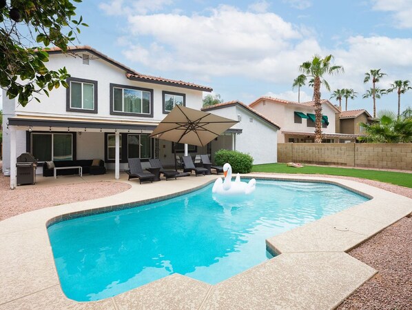 Spacious backyard with a private pool, sun loungers, BBQ, covered patio, outdoor dining, seating area, and corn hole!