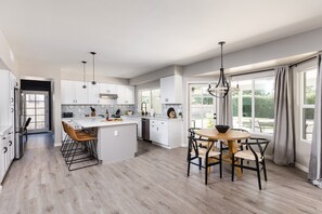 Fully equipped kitchen with stainless steel appliances, kitchen island with bar seating and dining area with seating for 4 guests.